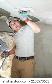 The master rubs the ceiling with a moisture-absorbing grater for lime plaster, repair work himself. - Shutterstock ID 2188573601