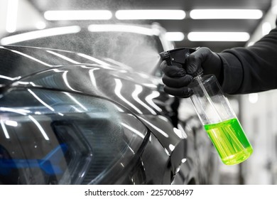Master sprays aerosol wax on the surface of the car before polishing. Detailing studio - Shutterstock ID 2257008497
