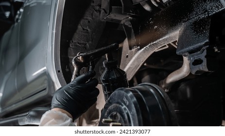 The master sprays an anti-corrosion compound on the bottom of the car. - Powered by Shutterstock