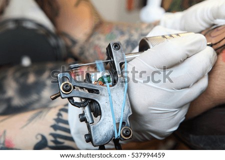 Master tattoo draws the black paint on the clients tattoo