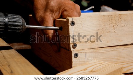 The master tightens a screw with a screwdriver while making a wooden box. Home workshop, carpentry, repair and production of wooden products.