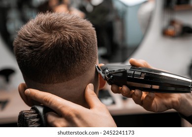 Master trims client hair with professional tool in luxury barbershop closeup. Barber does straight hairdo contour in men beauty salon - Powered by Shutterstock