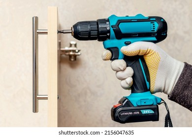 The master uses a cordless screwdriver to screw the handle to the cabinet door