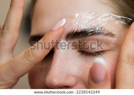 The master uses a plastic film during lamination of the eyebrows.
