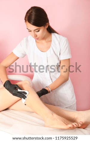 Master wipes client's feets, preparation for procedure of hair removal. Concept body care.