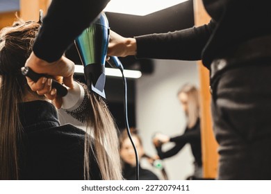 Master woman hairdresser dries the girl's hair with a hairdryer after washing in a beauty salon.