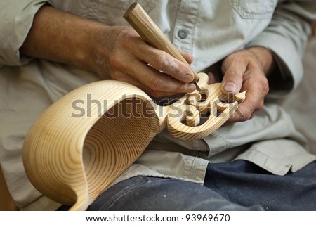 Master wood-carver made using a special knife wooden national dish - a ladle with a patterned handle. A fragment of a close-up of his hands