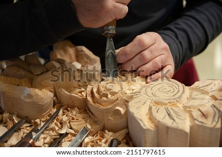 Master woodcarver at work. Wood shavings, gouges and chisels on the workbench. Close up.
