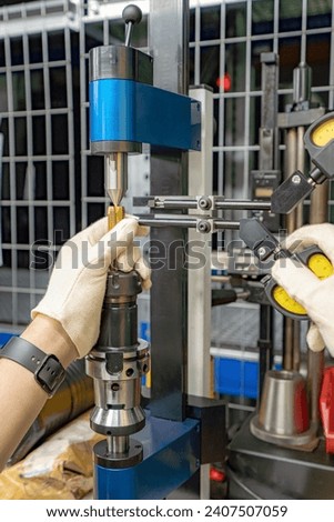 The master worker checks the CNC cutting tool for runout at the centers.