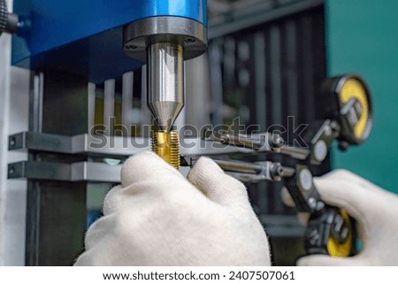 The master worker checks the CNC cutting tool for runout at the centers.