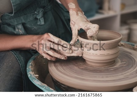Master works on potter's wheel, doing blank. Hands of person sculpt pot from white clay. Workshop for manufacturing potter's products. Concept: handmade, workshop, artist