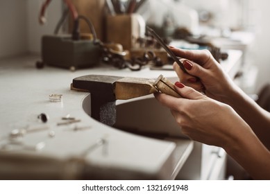 Master's hands. Side view of a female jeweler hands creating a silver ring at her workbench. Making accessories - Powered by Shutterstock