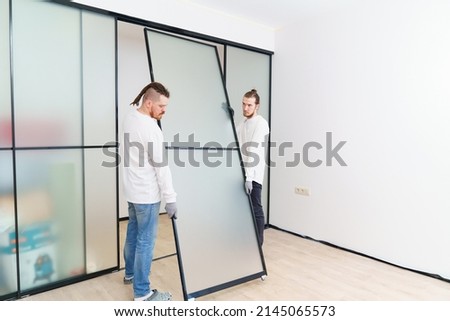 masters install the sliding doors of the wardrobe made of metal and glass. production and assembly of furniture to order. individual solutions for the interior of the home or office. small business