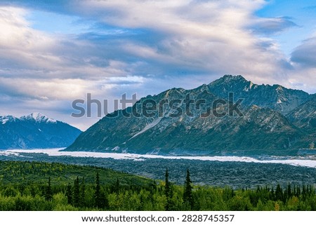 The Matanuska Glacier flows between rugged peaks into a forested valley along the Glenn Highway, Alaska.
