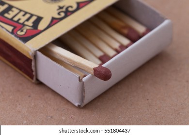 Match In Box, Carton Background. Macro Photography. Close-up Shot. Single Match In Open Match-box On Carton Underlay. Single Match Protruding From Matchbox