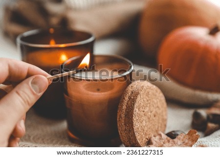 Match in hand lights a candle, cosiness concept.