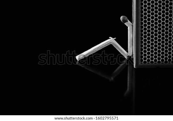 Match stick in thinking man style.\
Isolated black background. Match box. loneliness,\
sadness