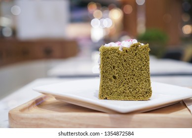 Matcha Chiffon Cake Topped With Sakura Pink Whipped Cream On White And Wooden Plate.