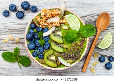 Matcha green tea breakfast superfoods smoothies bowl topped with chia, flax and pumpkin seeds, bee pollen, granola, coconut flakes, kiwi and blueberries. Overhead, top view, flat lay - Shutterstock ID 485710684