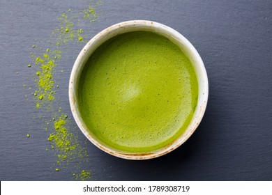 Matcha, green tea in a chawan cup. Grey stone background. Close up. Top view.