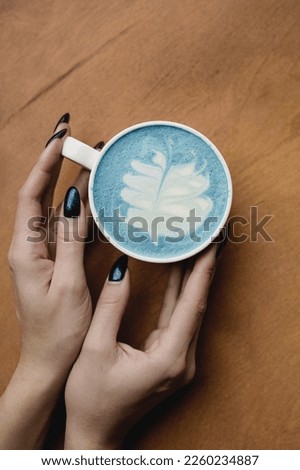 Matcha green tea, closeup, flowers and magazine, pattern on tea and coffee, green drink in a cafe, hands holding a mug of tea