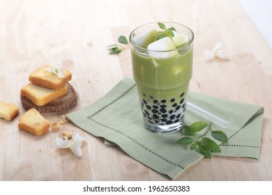 Matcha Latte Milk Bubble Tea With Cookies On Wooden Table Background. Matcha Iced Milk Tea Isolated Of Green Boba Tapioca Pearls Taiwan Milk Tea Drinks