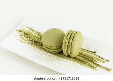Matcha macaroons dessert on white background. Creative still life of french meringue cookie macarons with matcha powder.