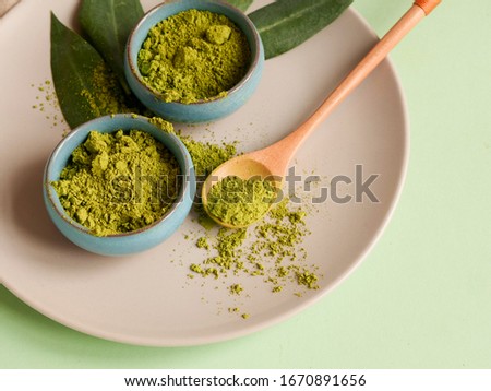 matcha tea on grey plate with spoon and leaf on grean background. Concept healthy drink, copyspace, close up