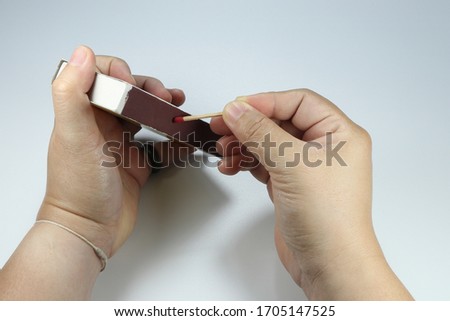 Match-fire Ignition and burning on the side of the box, white background. Old technology of lighting the flame. Woman's hand lid the fire.