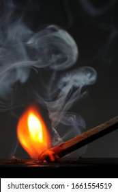 A Matchstick Process Of Ignition Just Moments Before The Flames Come Up. The Matchstick Produces A Lot Of White Smoke And Glows Hot At The Friction Point Of The Matchbox.