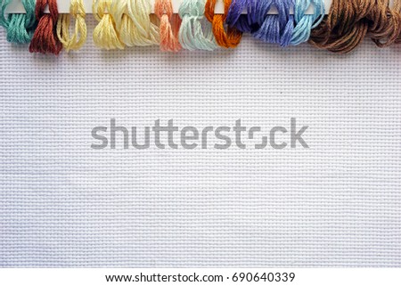 Material for embroidery cross-stitching with colored threads