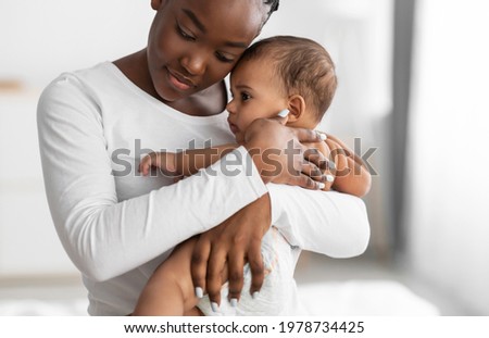 Maternity Concept. Portrait of young African American mother hugging and holding her baby on hands. Displeased infant feeling scared, woman conforting him. Copy space, blurred background Foto stock © 