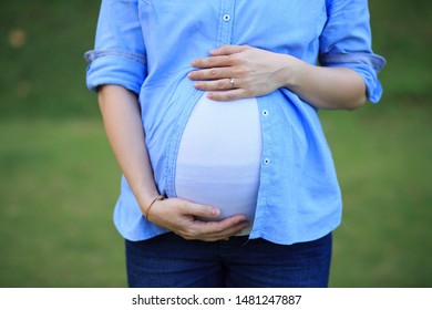 Maternity shot - Close up of a pregnant woman using both hand to hold her stomach