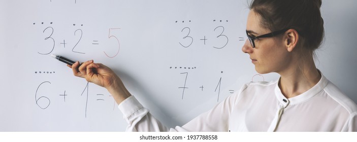math lesson - teacher showing simple mathematical equations on whiteboard in classroom
