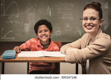 Math and science doodles against teacher assisting little boy with homework in classroom