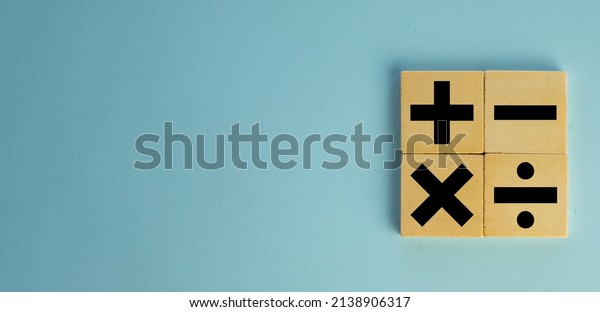 mathematic\
concept.,Black color of mathematical operations or Plus, minus,\
multiply, divide symbols on wooden cube over blue pastel background\
with copyspace for put text or\
logo.