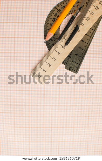 Mathematical\
instruments over the corner of a math graph paper with copy space\
for text. Math graphic tools\
concept.