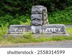 Mather Memorial Parkway sign pointing to Seattle and Yakima, made in classic US Park Service stone and iron style, exploring Mt. Rainier National Park in the summer
