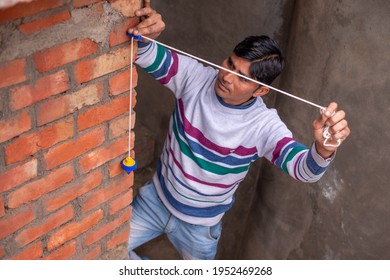 Mathura, Uttar Pradesh, India- January 18  2019: in Mathura mason using  a plumb bob for check brick wall.