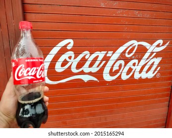 Mathura, Uttar Pradesh India- July 25 2021: Holding A Refreshing Bottle Of Black Soda Cold Drink Outside The Shop. Red Colored Coke Is A Popular Carbonated Coca Cola.