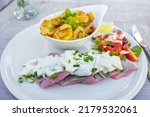 Matjes or soused herring, a mild salt fish with cream sauce containing onions, gherkins and apple, served with bratkartoffeln (German fried potatoes) and salad, selected focus, narrow depth of field