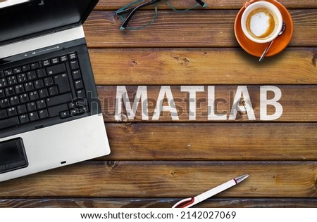 Matlab Programming Language. Word Matlab on wooden desk and laptop
