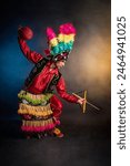 Matlachines Dancer from Coahuila Mexico A man in a colorful costume is holding a ball and a stick. The image has a lively and energetic mood, as the man is playing a game or performing a dance. 