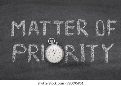 matter of priority phrase handwritten on chalkboard with vintage precise stopwatch used instead of O