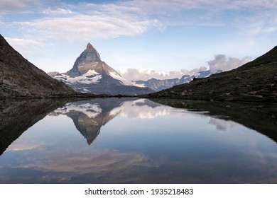 Matterhorn and reflection on the water surface at the sunrise. Famous Swiss mountain landscape. Riffelsee, Zermatt, Valais, Switzerland