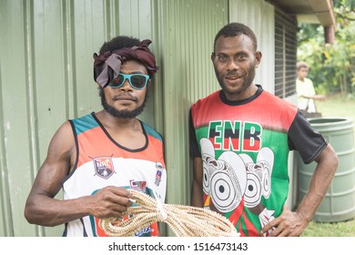 Matupit, East New Britain / Papua New Guinea - July 4, 2019: Two Papua New Guinean Men Of The Tolai Indigenous People With Colorful T Shirts Pose In Matupit Village While Holding Shell Money Coil