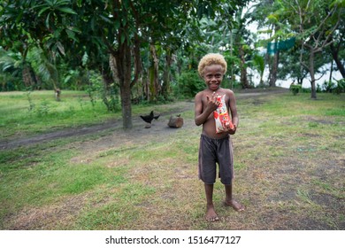 Matupit, East New Britain / Papua New Guinea - July 4, 2019: Naturally Blonde Black Girl Of The Tolai Indigenous People Living In The Pacific Island Of New Britain, Holding A Package Of Rice 