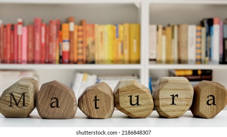 Matura Text (polish Word For End Of School Exam) Written On Wooden Blocks In Front Of Book Shelves.