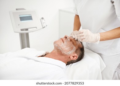 Mature 50 Years Old Man Receiving Moisturizing Revitalizing Rejuvenating Anti-aging Beauty Treatment In Modern Wellness Spa Clinic