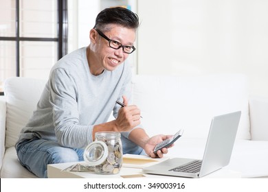 Mature 50s Asian man giving thumb up while counting on money using calculator and laptop computer. Saving, retirement, retirees financial planning concept.  - Shutterstock ID 349003916